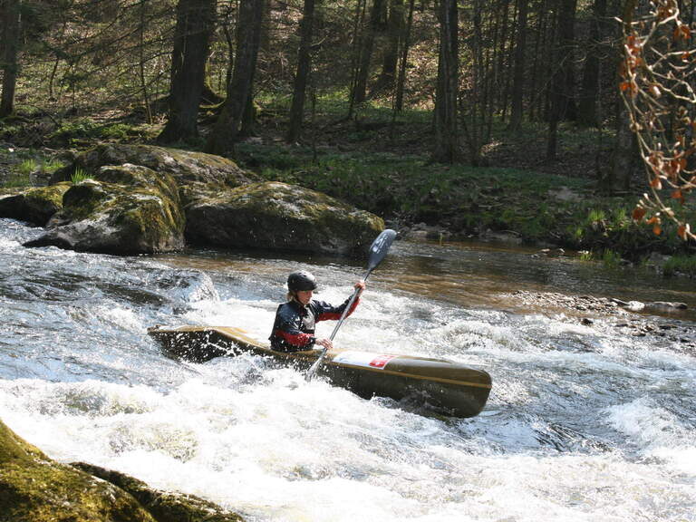 Ein Sportler navigiert gekonnt mit seinem Kajak durch Stromschnellen inmitten der Natur von Bodenmais.