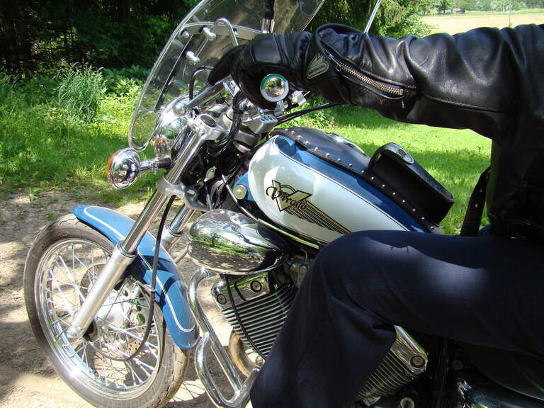 Nahaufnahme eines geparkten Motorrads mit Lederhandschuh und Windschutzscheibe.